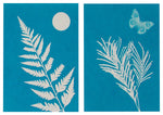 Load image into Gallery viewer, Two samples of solar print art using blue solar print paper and outdoor objects - one with fern style leaves and the other with tree needles and a butterfly
